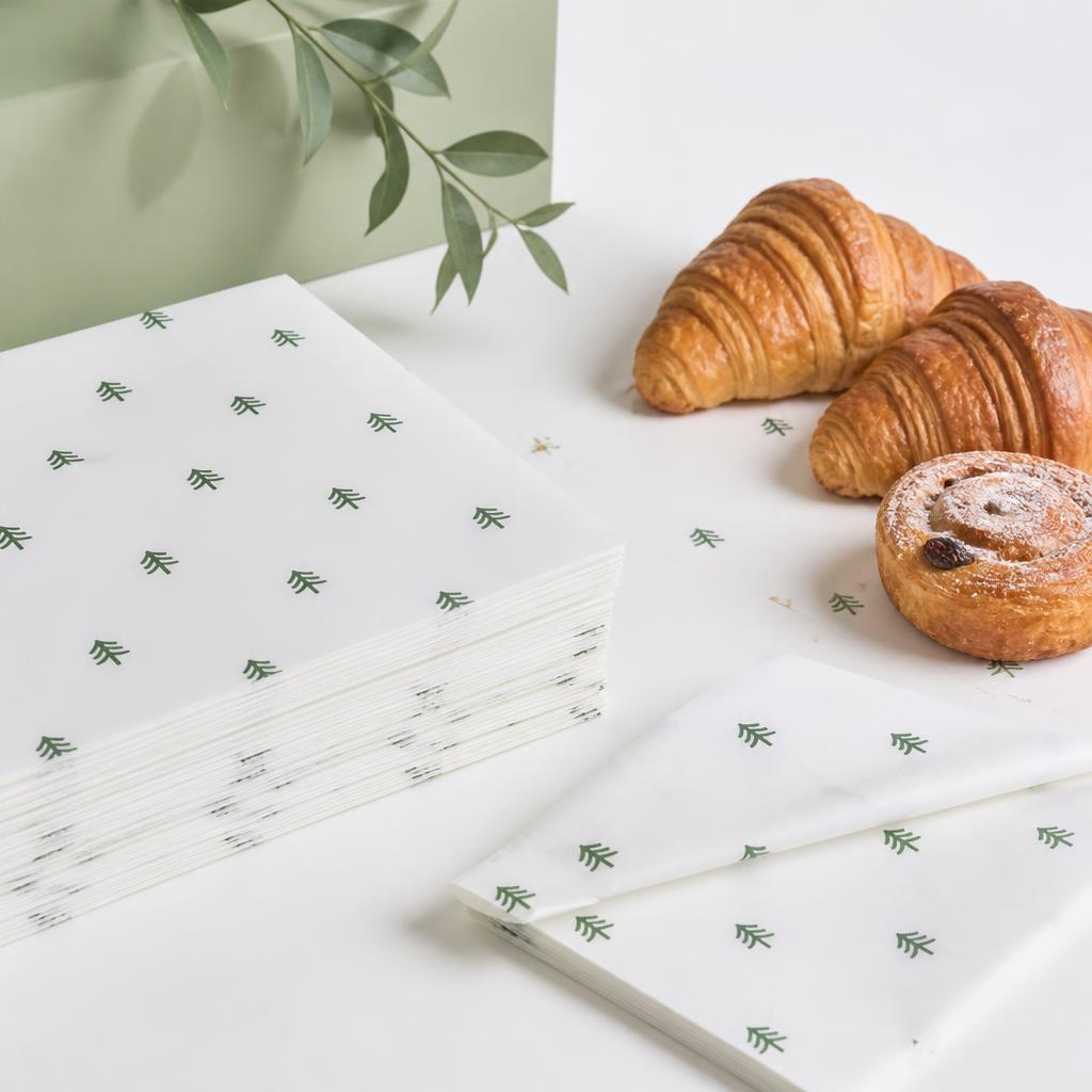 Greaseproof paper sheets arranged with bakery pastries
